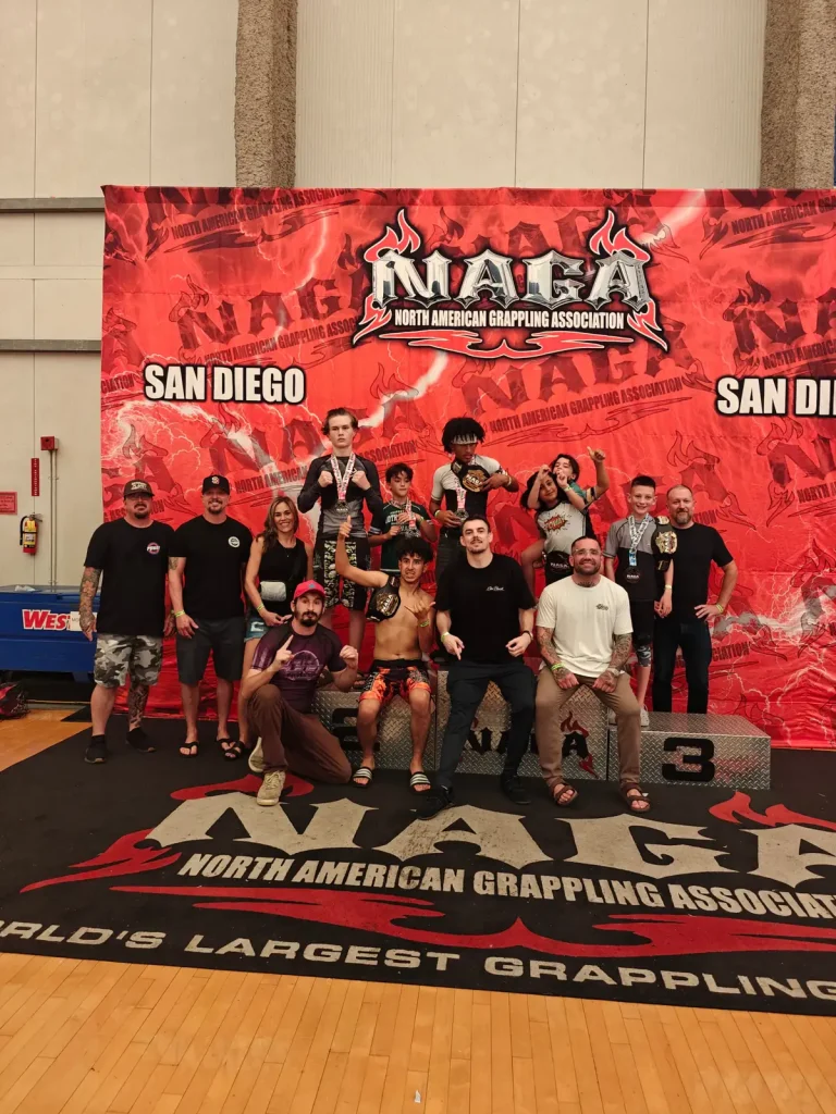 Youth grappling competitors and supporters posing together at the NAGA San Diego championship podium